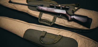 Black rifle with scope and brown gig bag