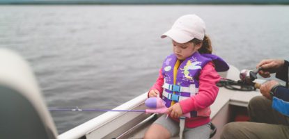 A young girl fishing while on a motorboat