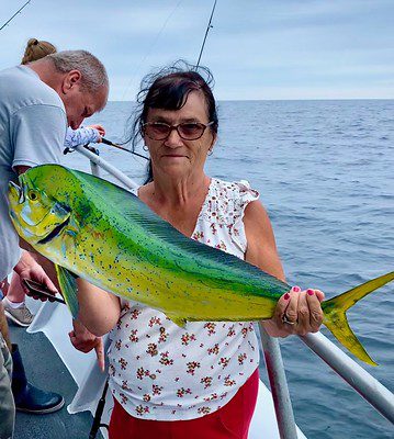  Photo of woman on a boat holding a green and yellow fish