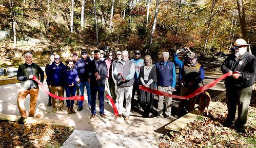 Photo of group of people cutting a ribbon in an outdoors area