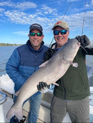 Photo of two men holding a catfish